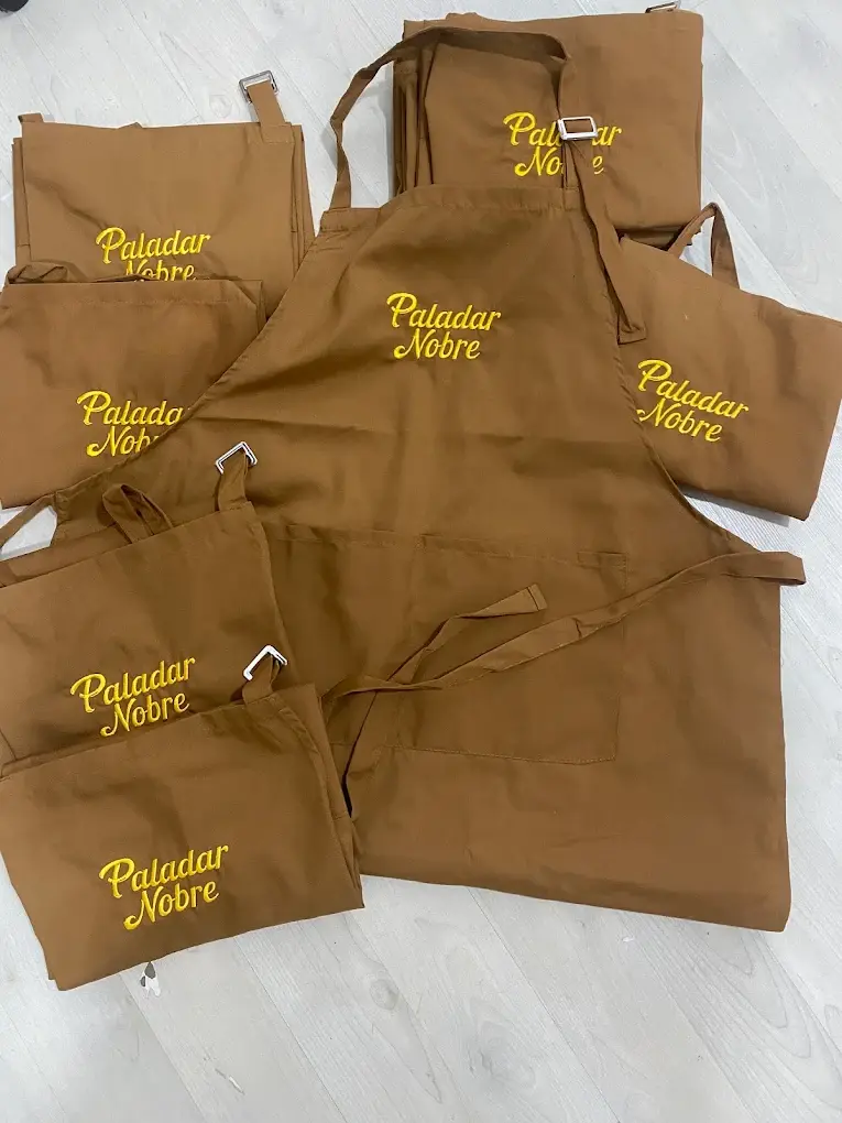 Aventais castanhos com Paladar Nobre bordado a amarelo.