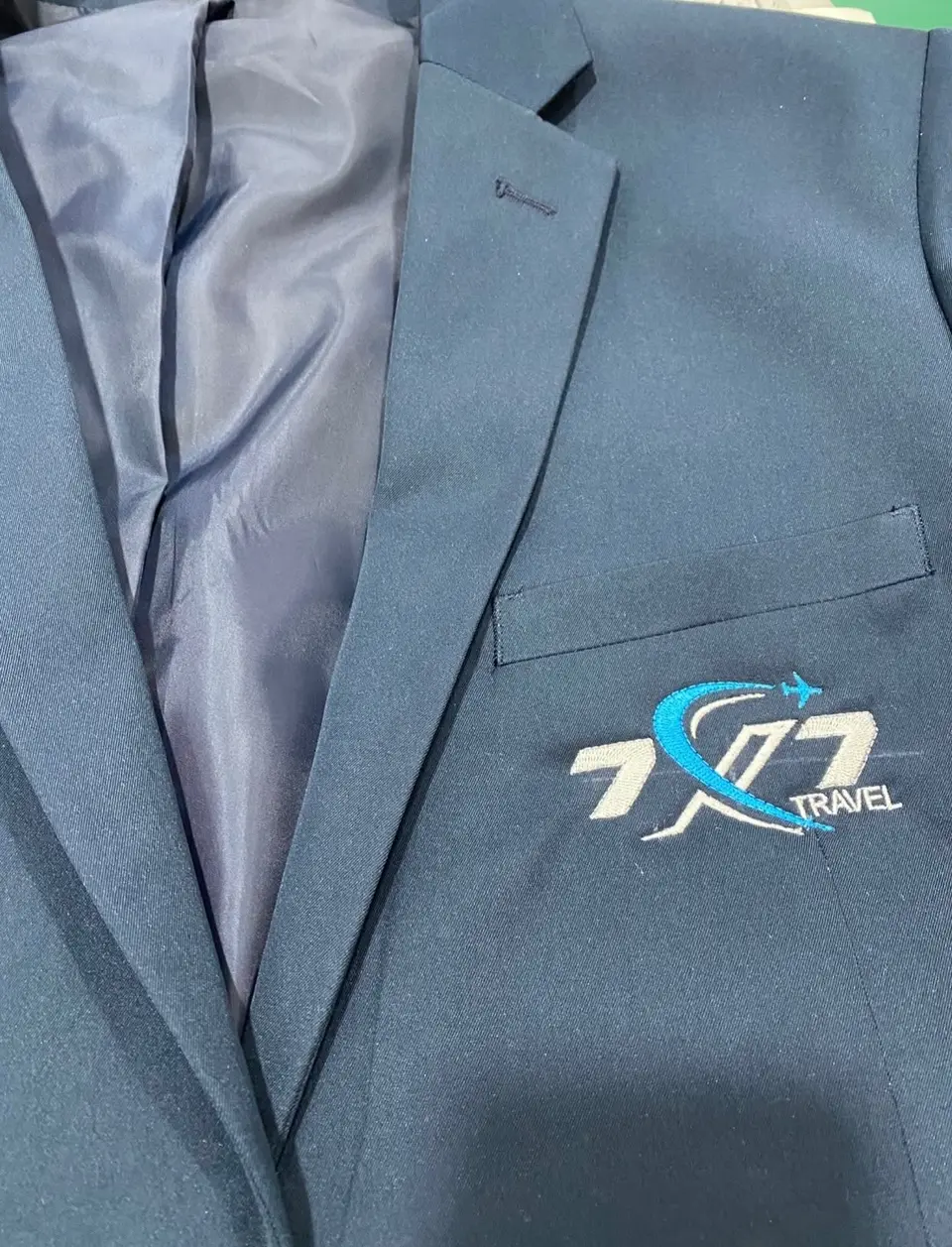 Blazer azul com o logótipo 7X7 Travel bordado no bolso do peito.