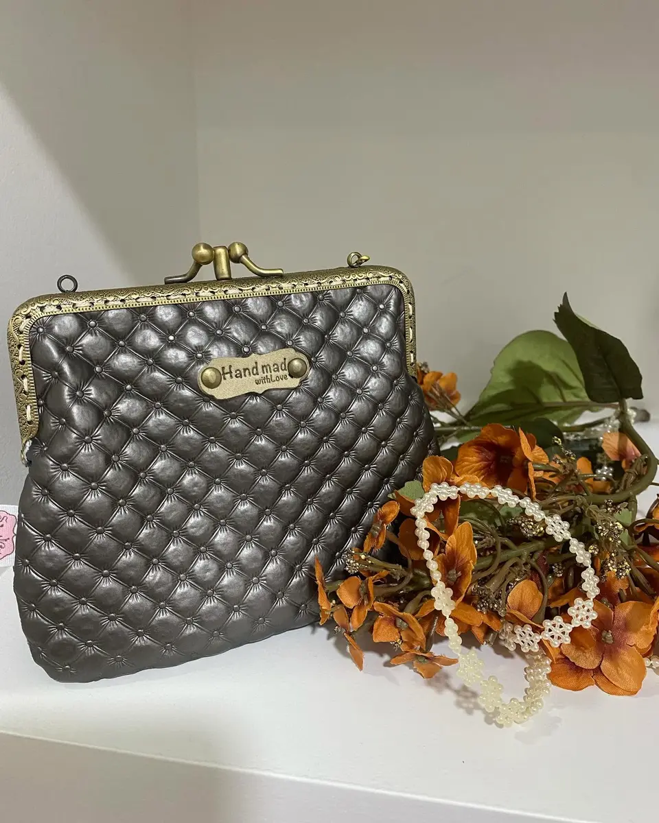 Bolsa de boquilha acolchoada em cinza-chumbo com etiqueta Handmade.