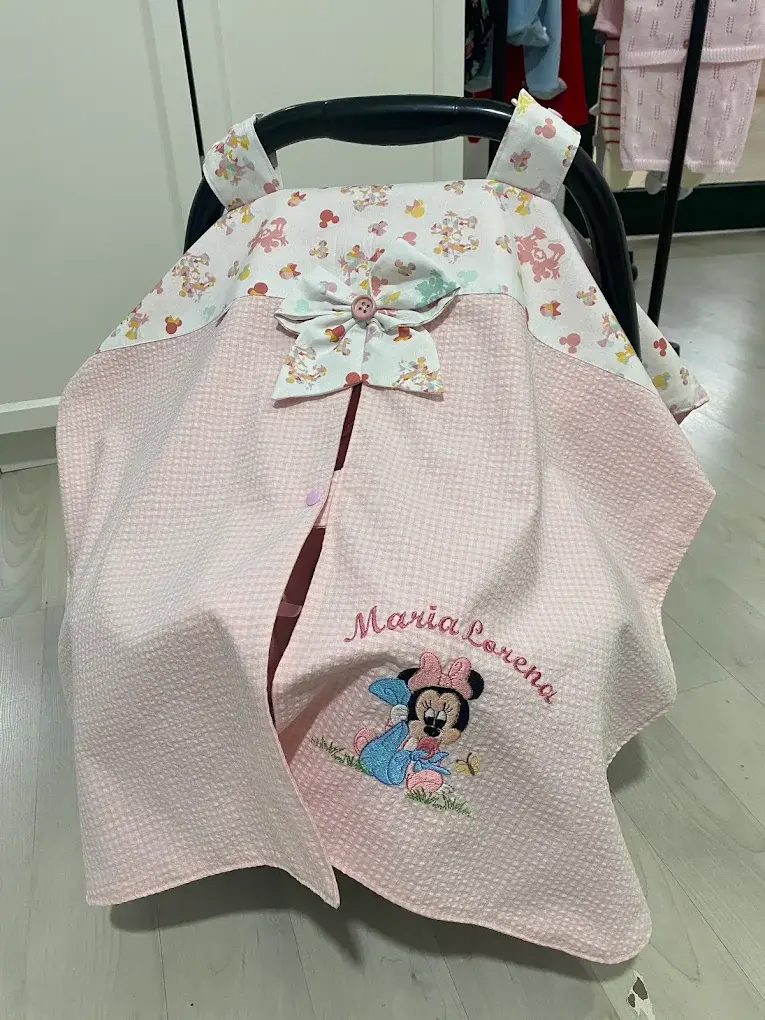 Capa rosa para a cadeira de bebé com o nome Maria Lorena e a Minnie bordados, e laço floral.