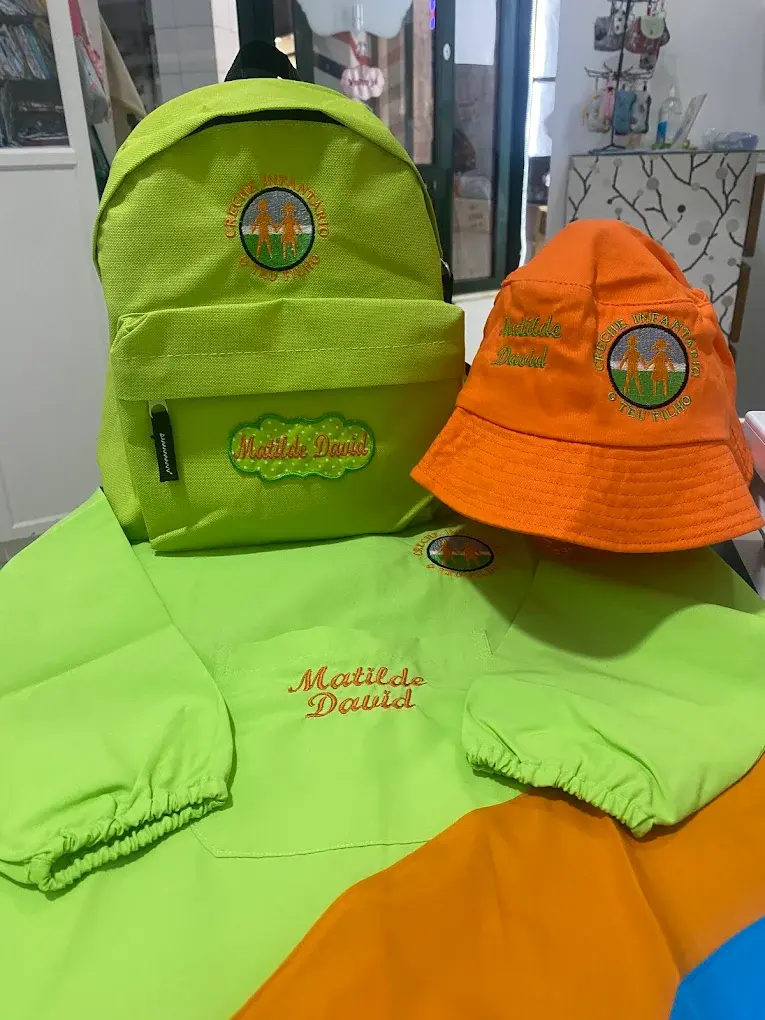 Mochila verde, chapéu laranja e bibe verde com o nome Matilde David bordado.