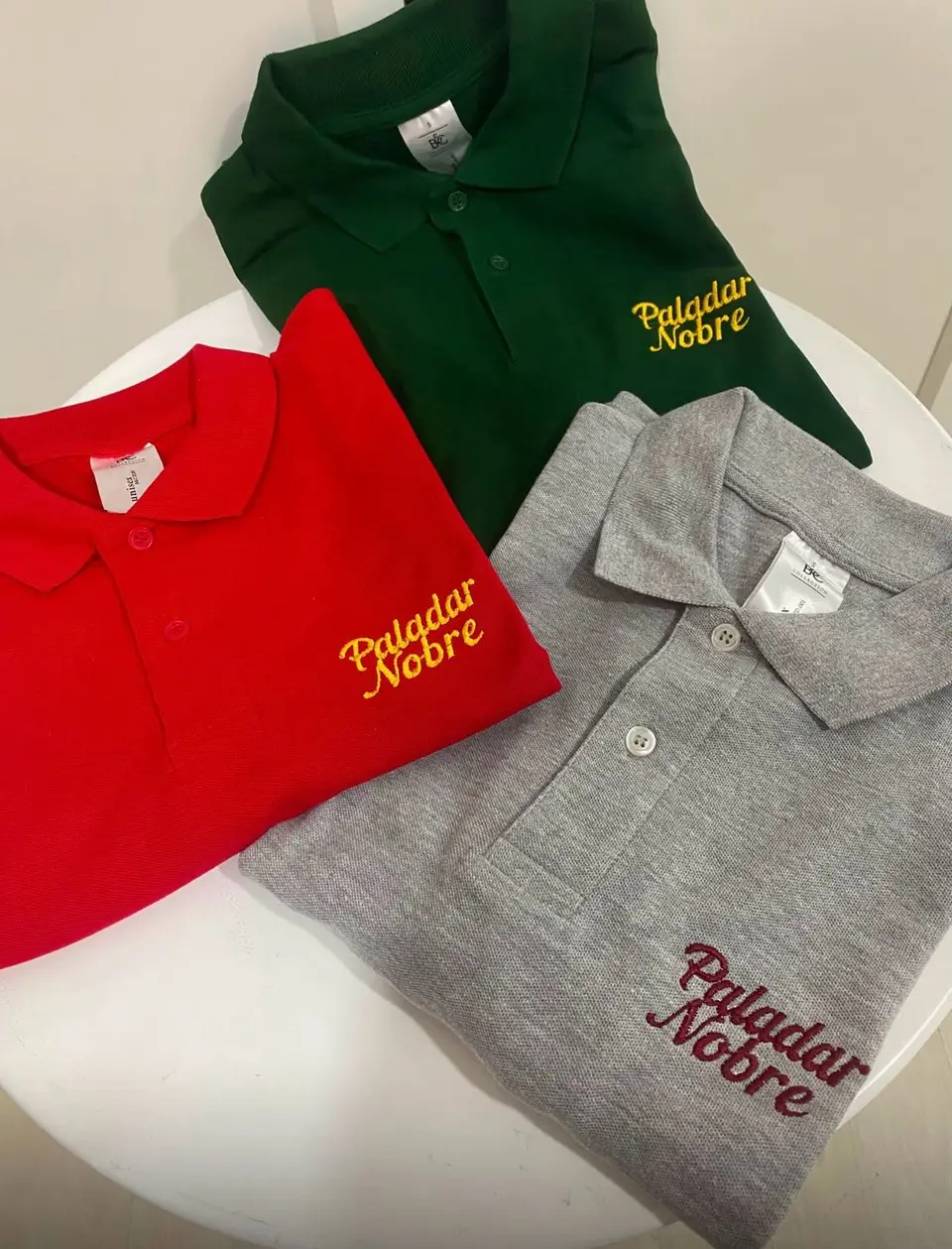Polos verde, vermelho e cinzento com Paladar Nobre bordado.
